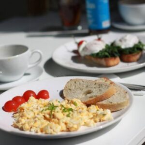 Plate of scrambled eggs, toast, and tomato