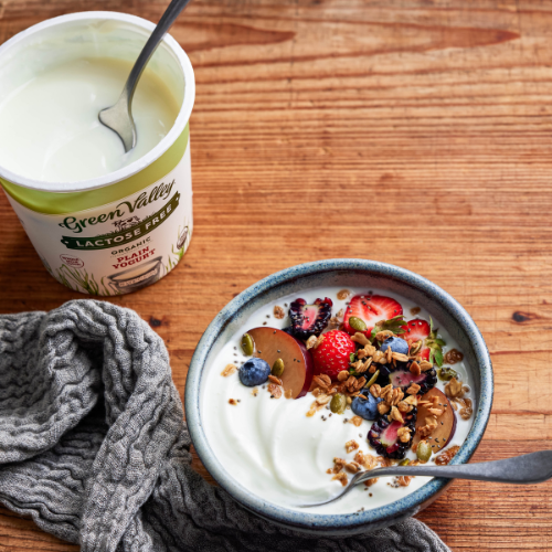 bowl of yogurt with granola and berries and a container of green valley creamery yogurt