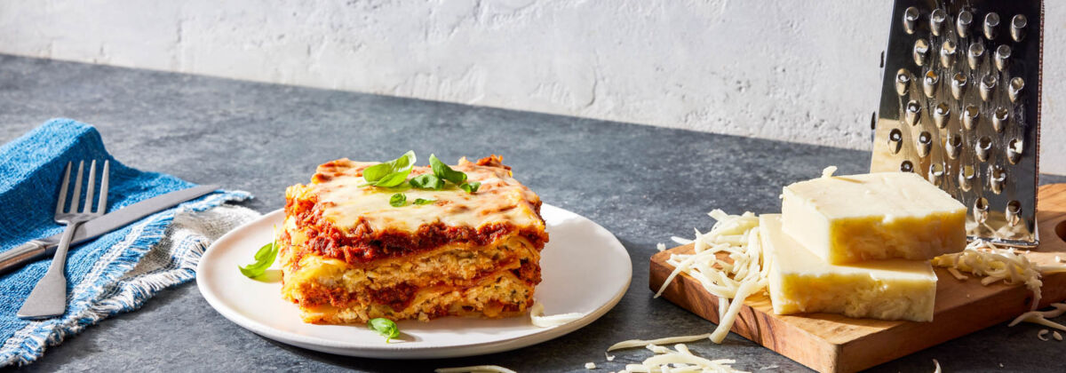 a slice of lasagna with a block of cheese