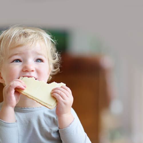 a toddler eating a slice of cheese